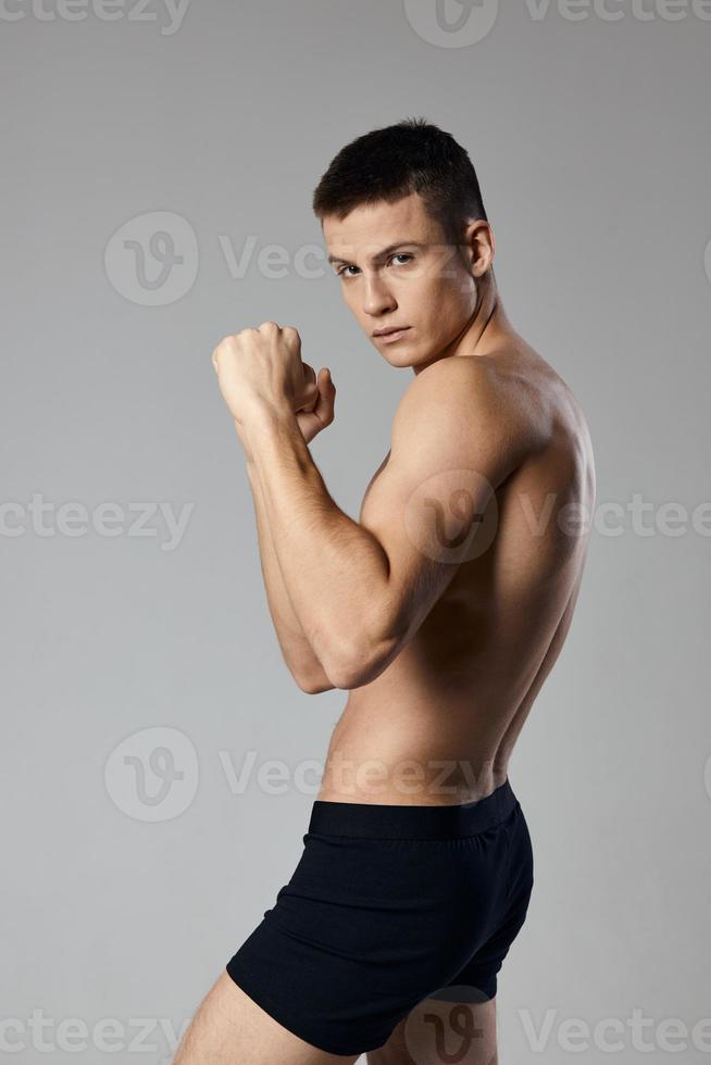 Athlet im schwarz kurze Hose nackt Torso Bodybuilder grau Hintergrund abgeschnitten Aussicht Kopieren Raum foto