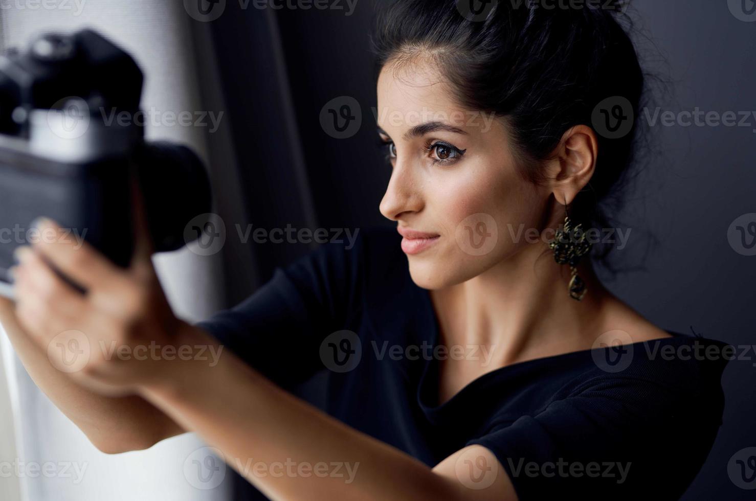 ziemlich Frau halten ein Kamera in der Nähe von das Fenster Dekoration Mode Lebensstil Studio foto
