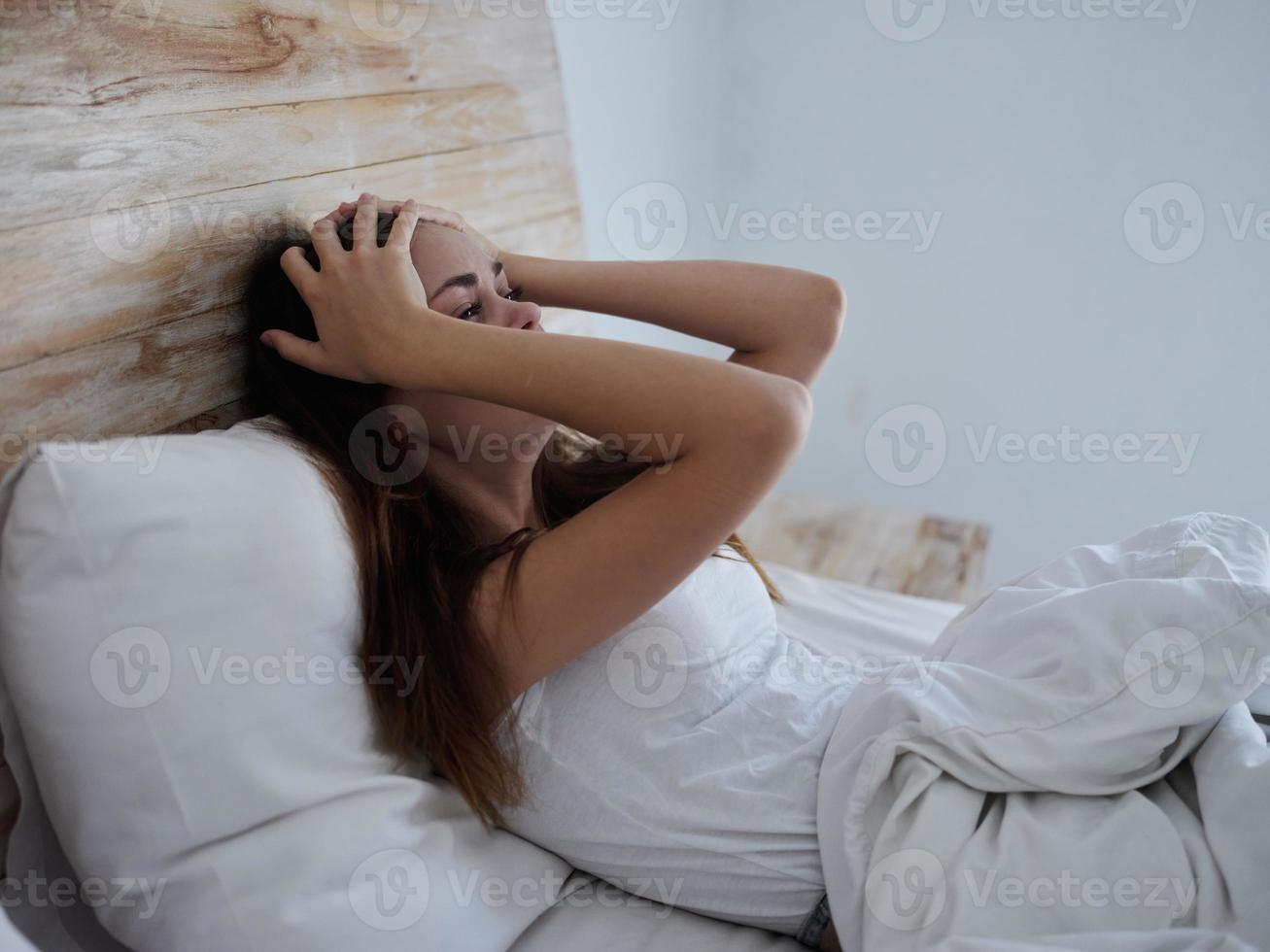 Frau mit Temperatur Lügen im Bett Hände auf Kopf Emotionen foto