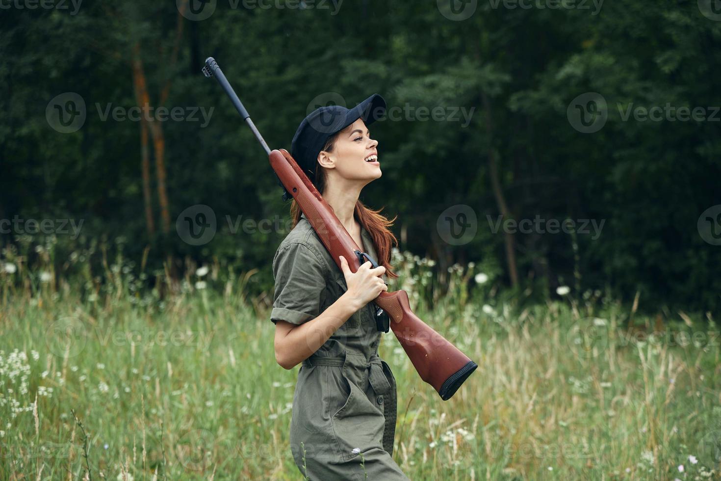 Frau auf draussen Seite Aussicht von halten ein Waffe im das Hände von ein Grün Overall schwarz Deckel foto
