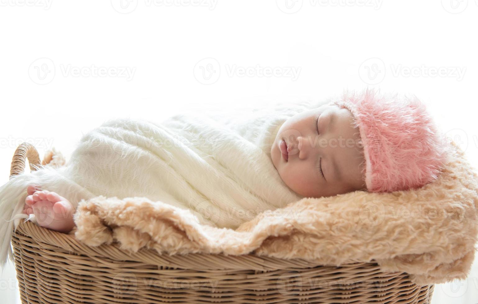 Neugeborenes Baby, das in einem Korb auf weißem Hintergrund schläft foto