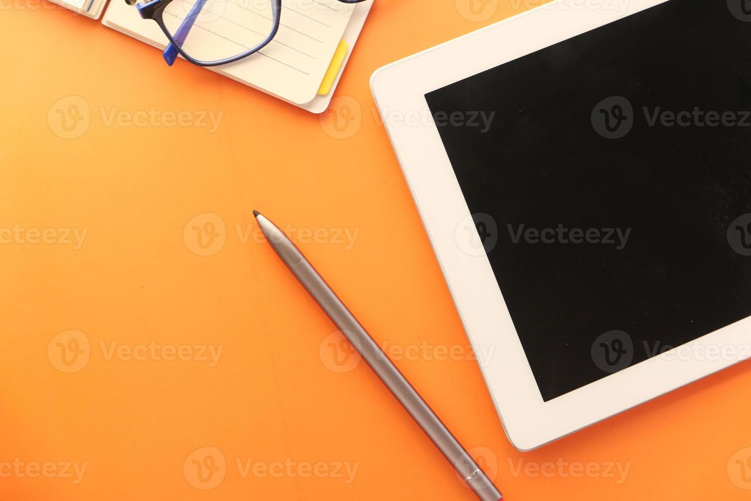 digitales Tablet und Stift auf orangefarbenem Hintergrund foto