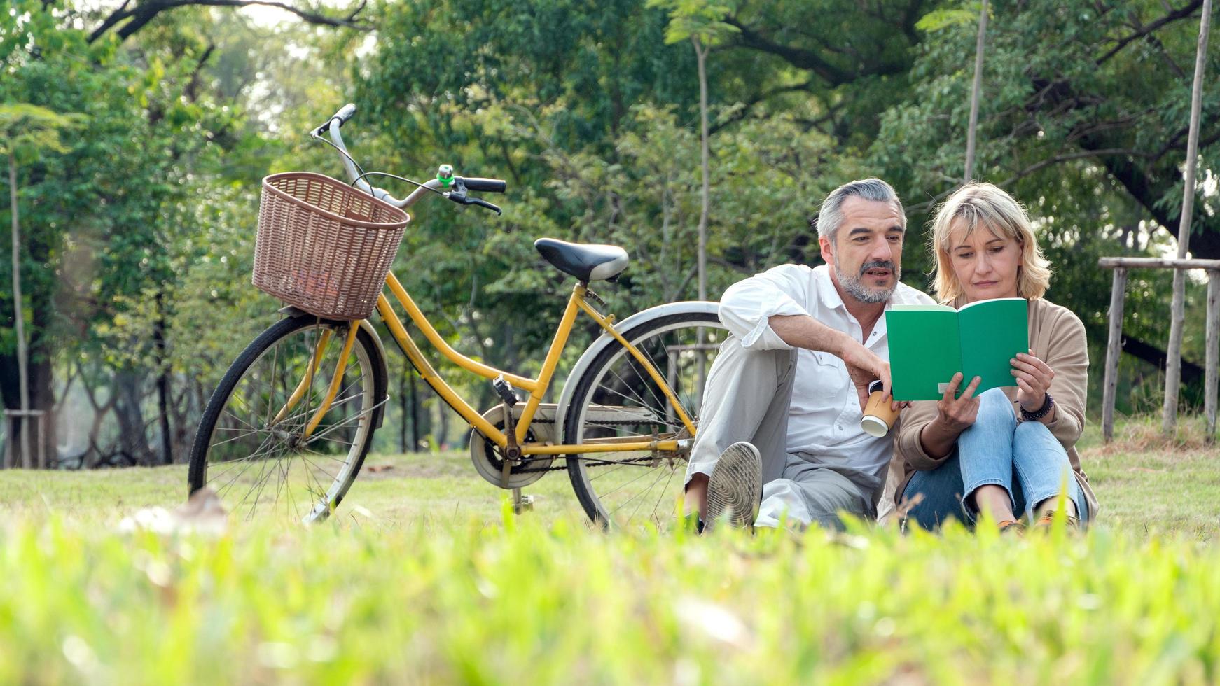 reifes Paar, das ein Buch in einem Park liest foto