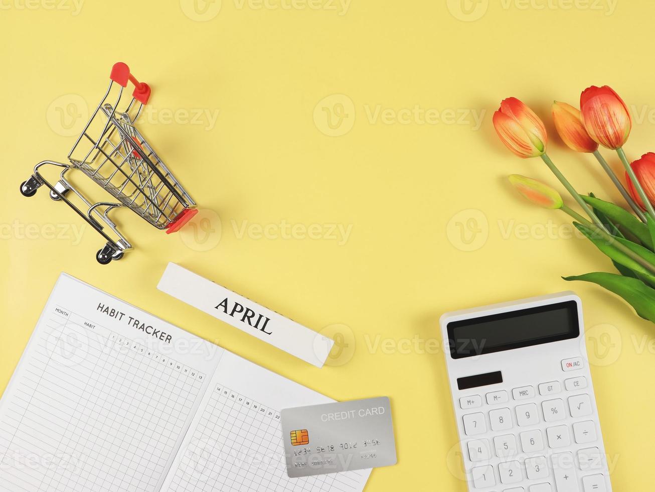 eben Layout von Gewohnheit Tracker Buch, Weiß Taschenrechner, Anerkennung Karte, Einkaufen Wagen oder Einkaufen Wagen und Tulpen auf Gelb Hintergrund. foto