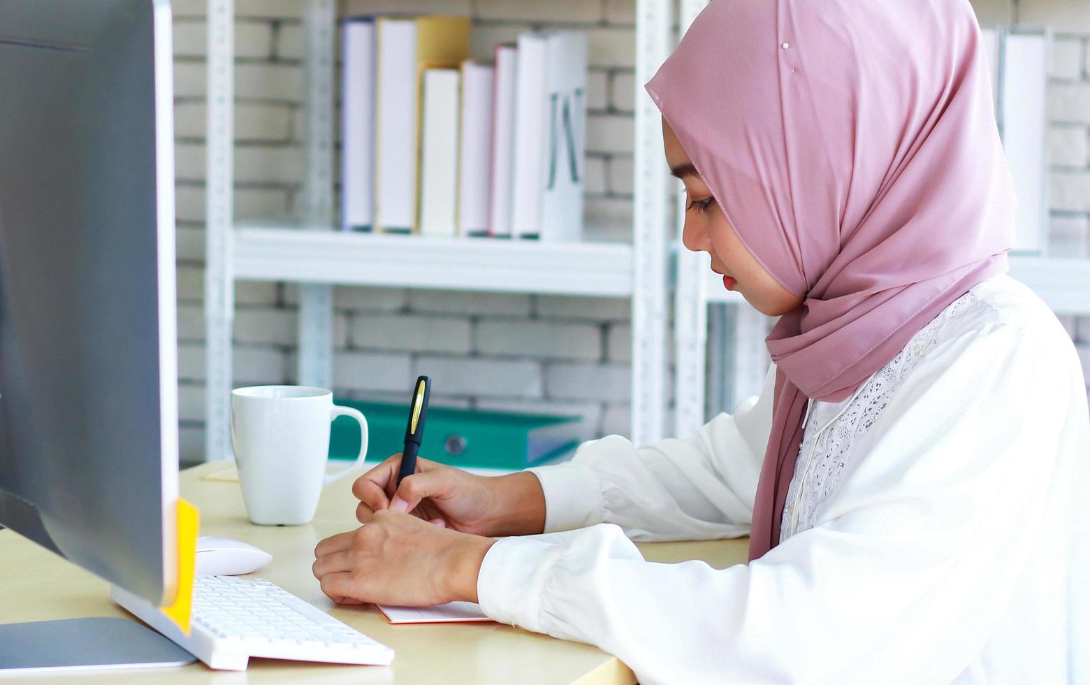 schöne muslimische Geschäftsfrau, die glücklich im Büro arbeitet foto