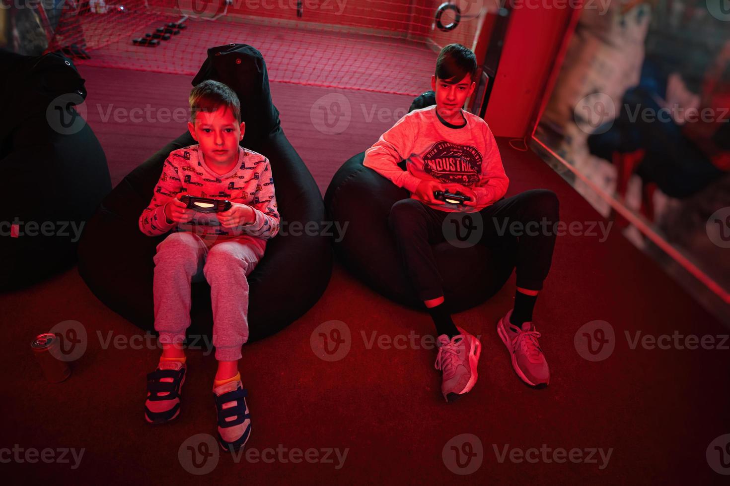 zwei Jungs Spieler abspielen Gamepad Video Spiel Konsole im rot Spielen Zimmer. foto