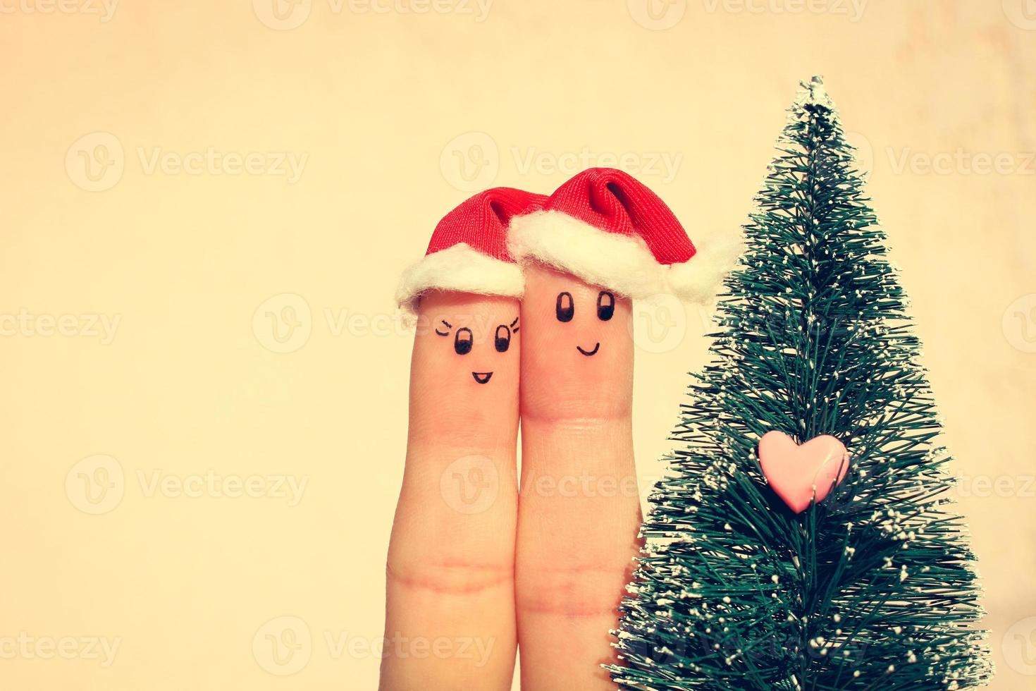 Finger Kunst von Paar feiert Weihnachten. Konzept von Mann und Frau Lachen im Neu Jahr Hüte in der Nähe von Weihnachten Baum. getönt Bild foto