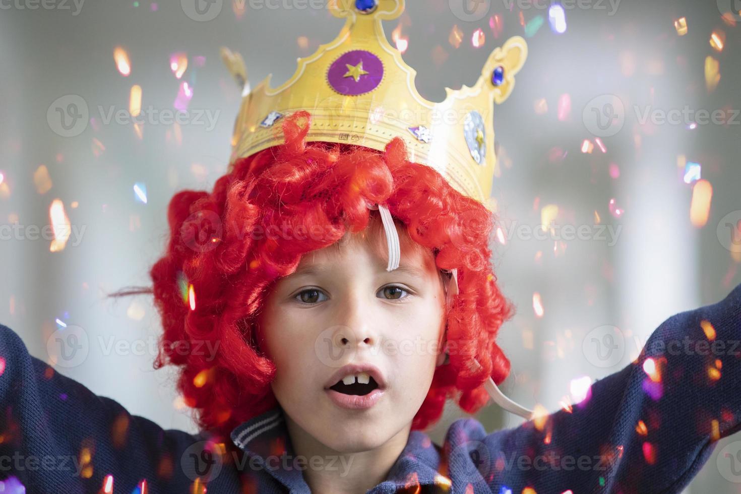 Kind im ein rot Perücke und ein Krone. Clown Junge im glänzend Süßigkeiten foto