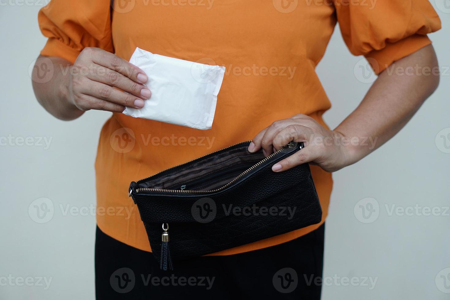 Closeup Frau hält Damenbinde für die Menstruation, um sie vor dem Ausgehen in die Tasche zu stecken. Konzept, Damenhygieneprodukt für den Tag der Periode. Frau im Gesundheitswesen. monatliche Intimpflege. foto