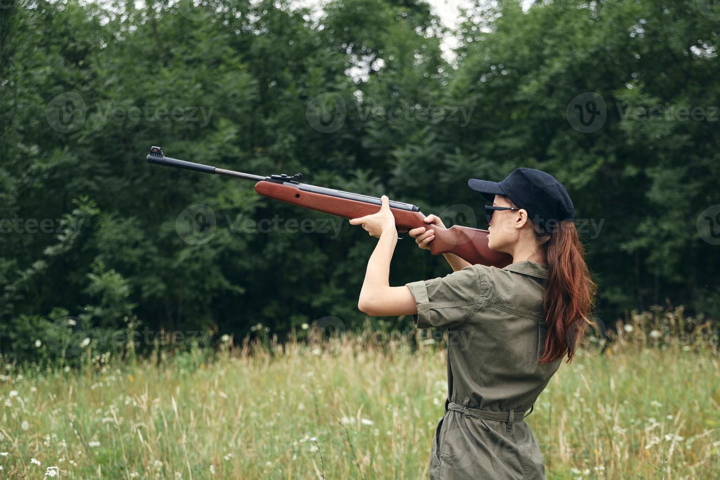 Militär- Frau Jagd Sicht Gewehr Grün Overall Grün Bäume foto