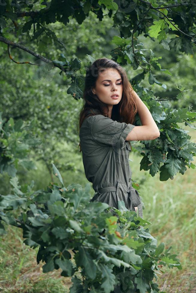 Frau im das Wald mit geschlossen Augen im ein Grün passen frisch Luft foto