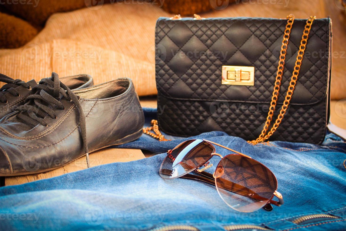 Sonnenbrille, Jeans, Handtasche und alt Schuhe. getönt Bild. foto