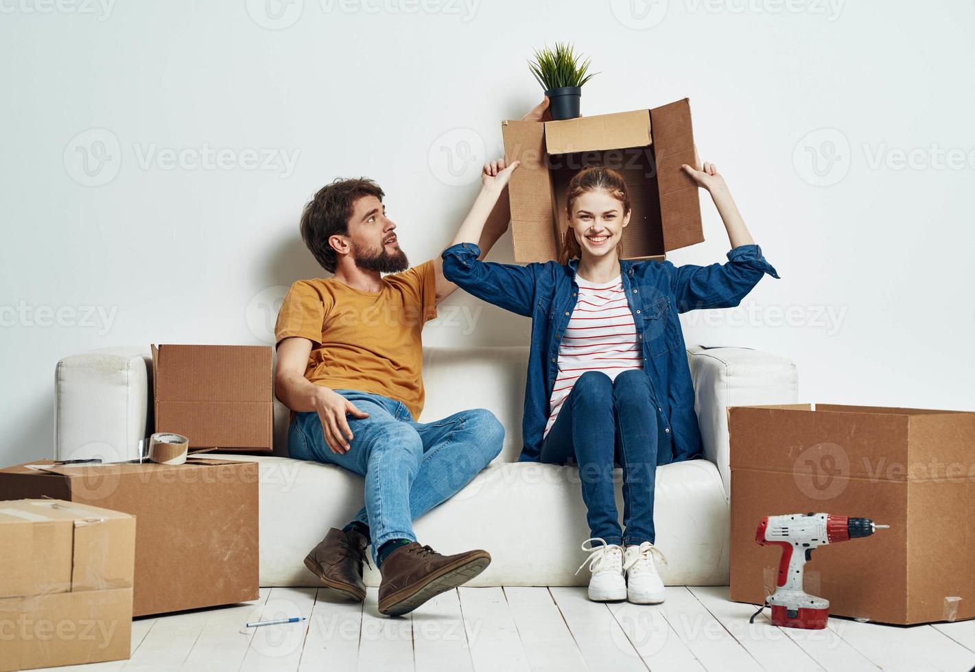 Mann und Frau sind Sitzung auf Sofa mit Kisten von Werkzeuge ziehen um Innere foto
