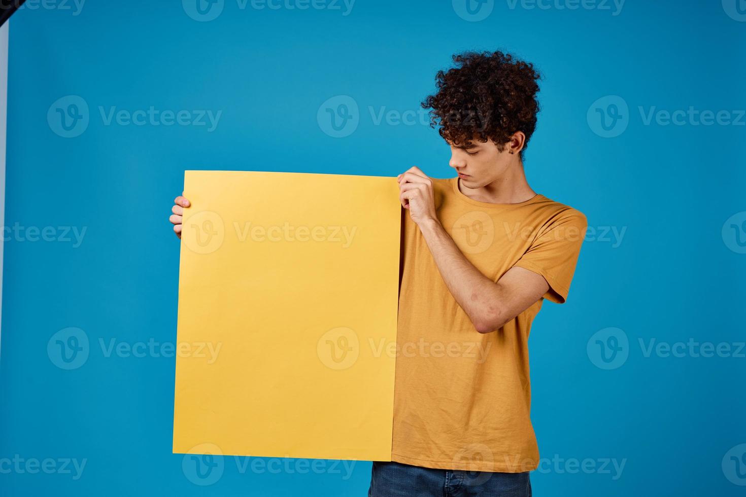 heiter Mann mit Gelb Poster Attrappe, Lehrmodell, Simulation Blau Hintergrund Studio foto