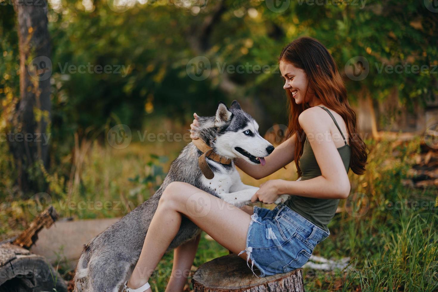 Frau und ihr heiser Hund glücklich spielen draußen im das Park unter das Bäume Lächeln mit Zähne im das Herbst gehen mit ihr Haustier foto