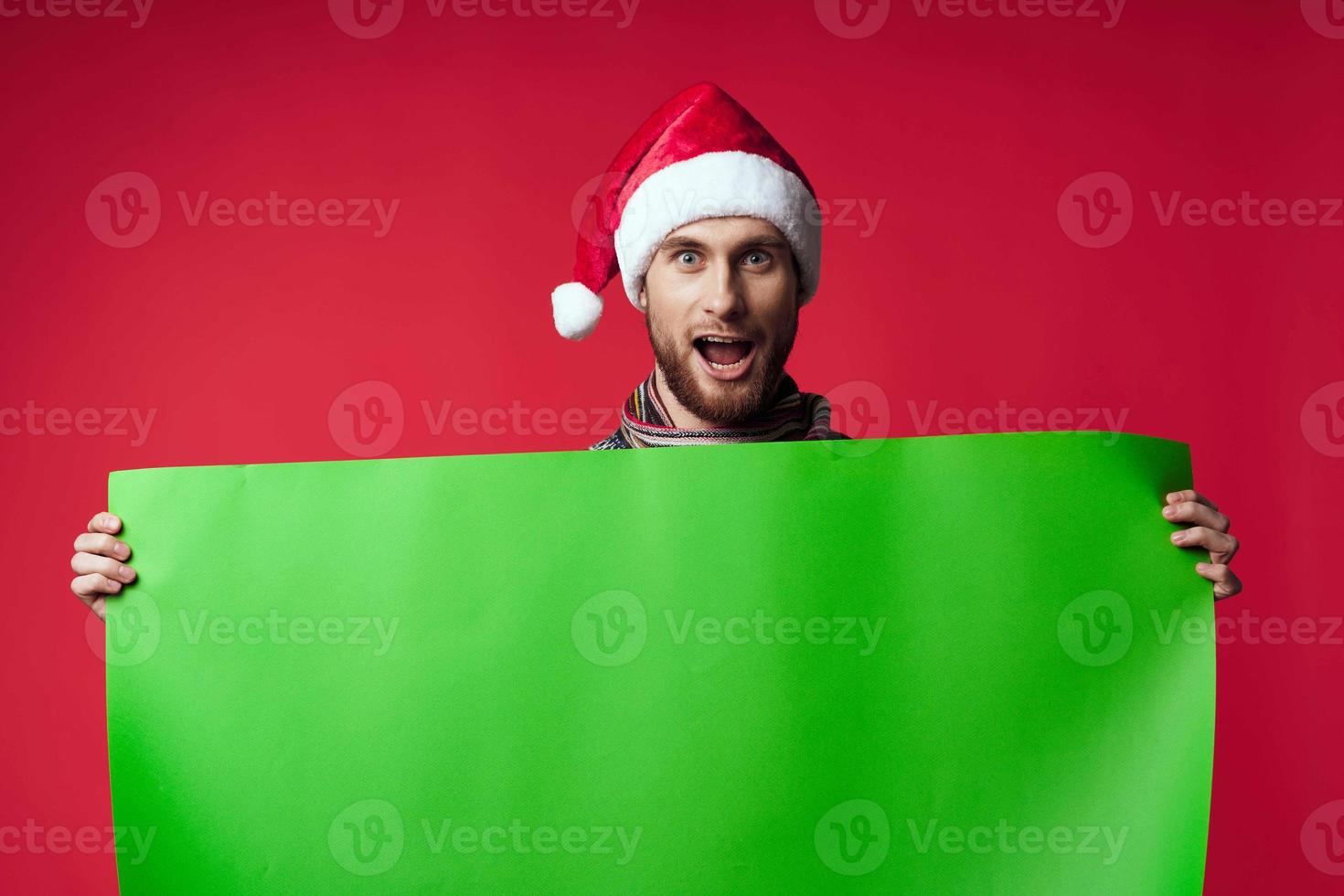 emotional Mann im ein Santa Hut halten ein Banner Urlaub rot Hintergrund foto