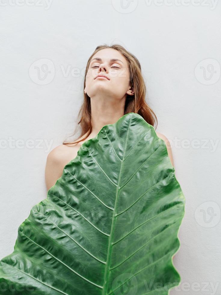 Frau mit geschlossen Augen nackt Körper Grün Palme Blatt Licht Hintergrund foto