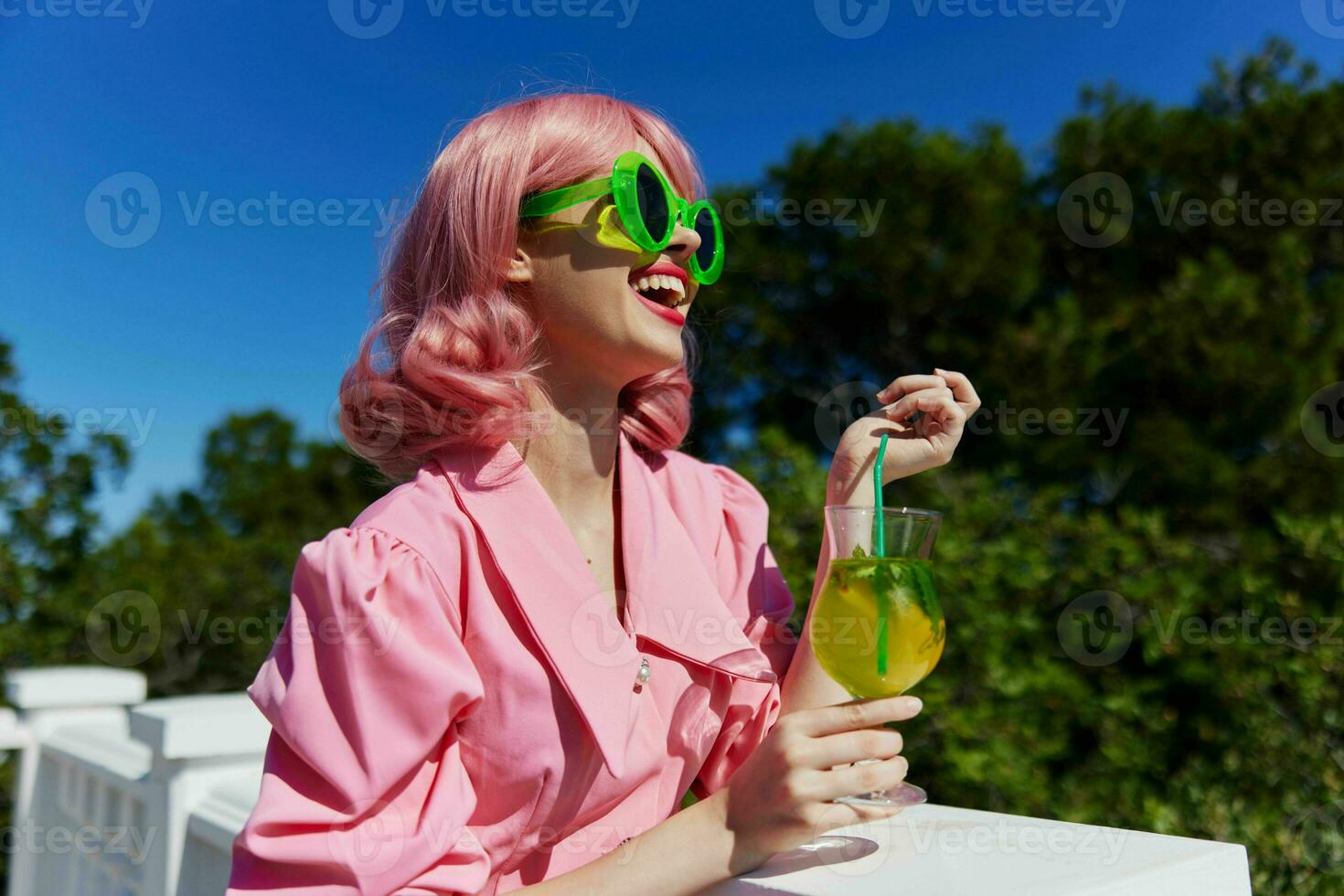 modisch Frau im Rosa Kleid draußen mit Cocktail Sommer- Tag foto