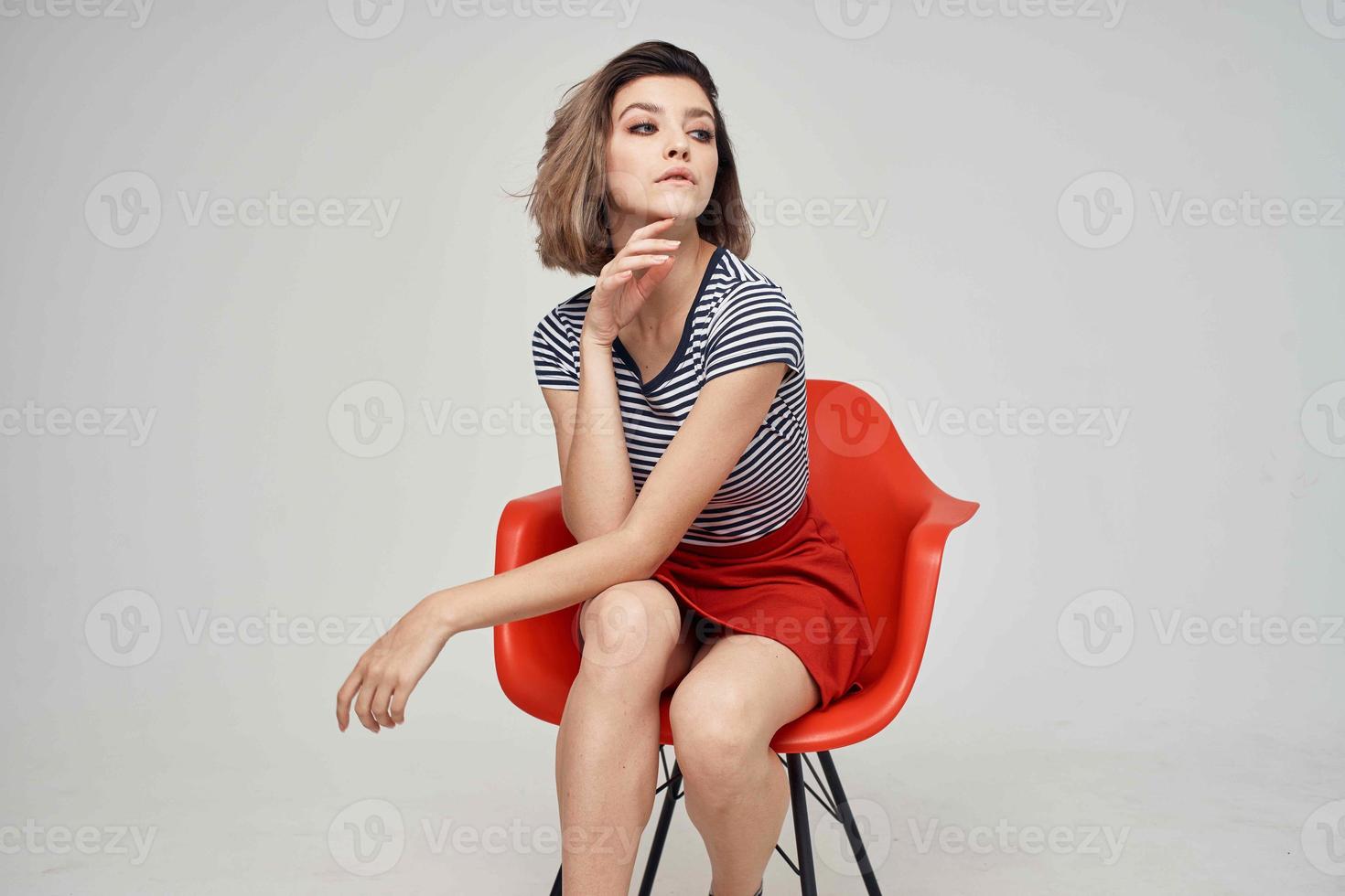 Frau mit Brille Sitzung auf das rot Stuhl Licht Hintergrund Lebensstil foto