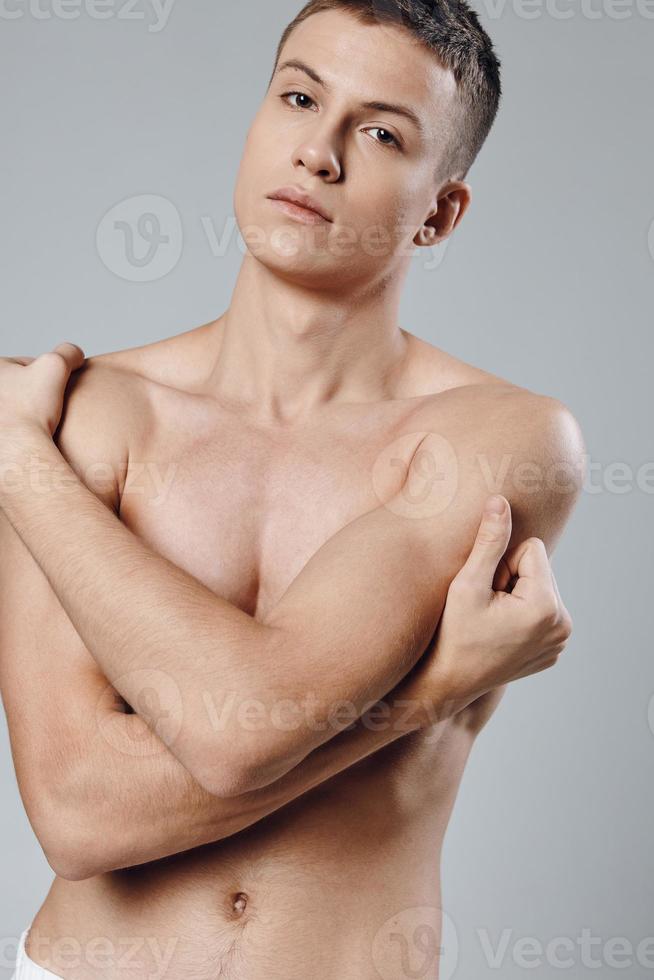 Athlet mit gepumpt oben Muskeln auf seine Bauch Umarmungen selbst mit seine Hände foto