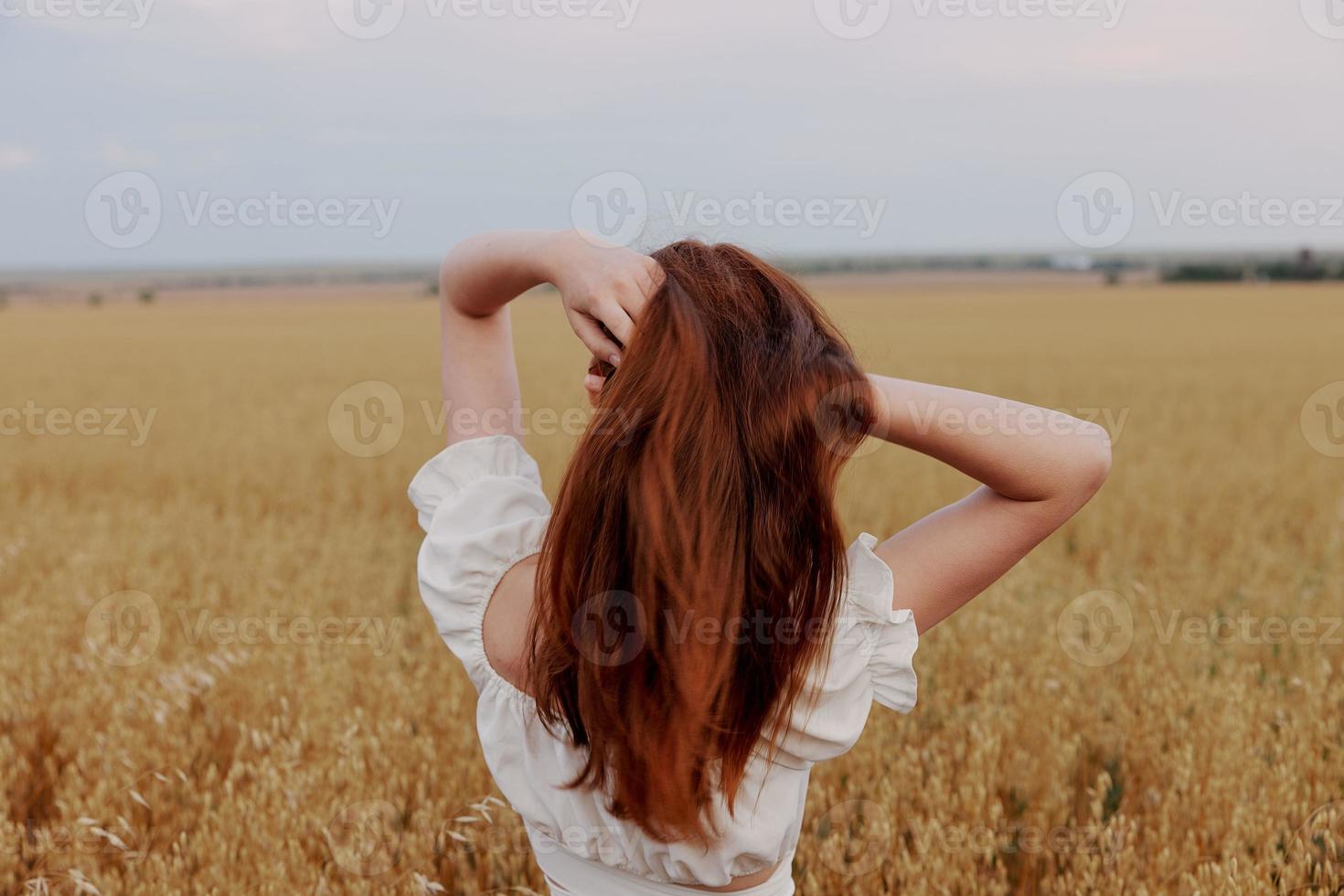 rothaarig Frau halten Haar im ein Feld im Natur foto