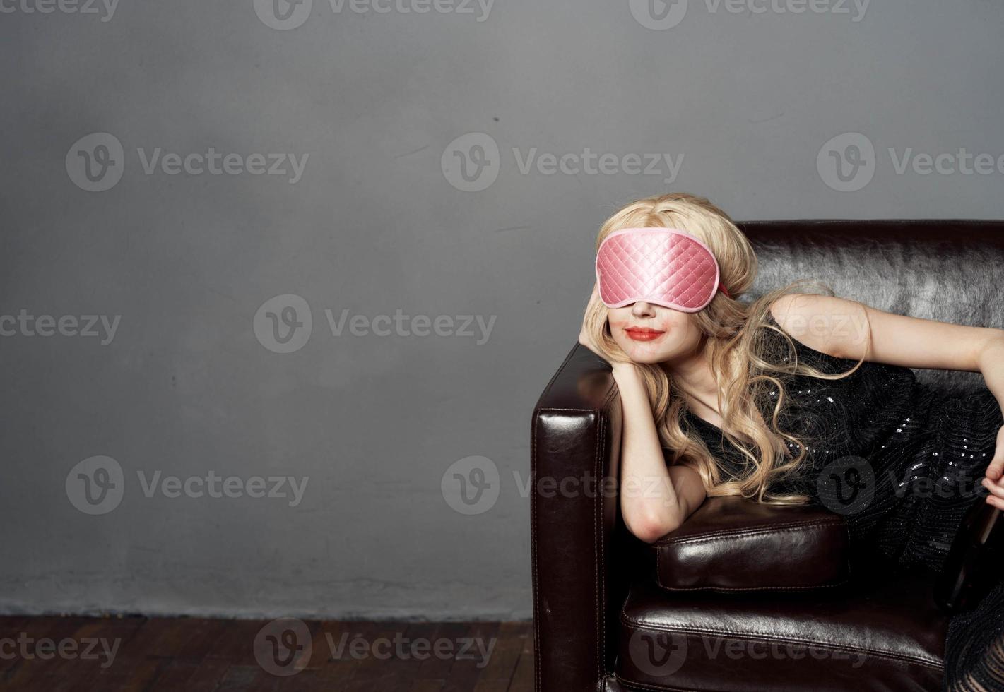 ein Frau mit ein Rosa Schlaf Maske Lügen auf das Couch mit ein Flasche von Bier im ihr Hand foto