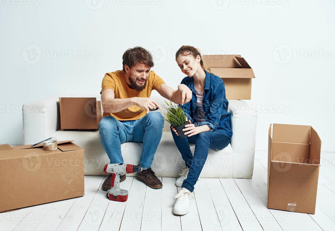 verheiratet Paar auf ein Weiß Sofa im das Zimmer Innere mit Kisten von Kommunikation Dinge foto