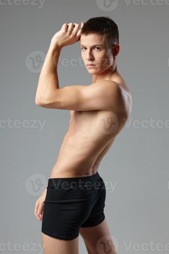 Mann im schwarz kurze Hose hält Hand in der Nähe von Kopf posieren trainieren zu Bodybuilder foto