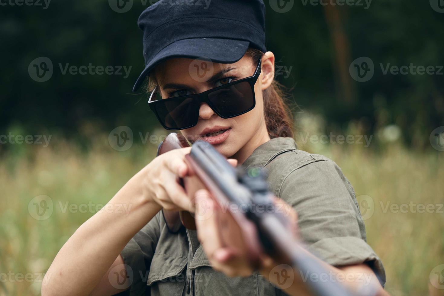 Frau Soldat Zielen Schrotflinte Sonnenbrille Nahansicht frisch Luft Grün Bäume foto