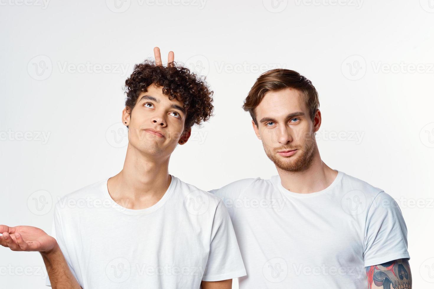 zwei Männer im Weiß T-Shirts gestikulieren mit ihr Hände Freundschaft Studio foto