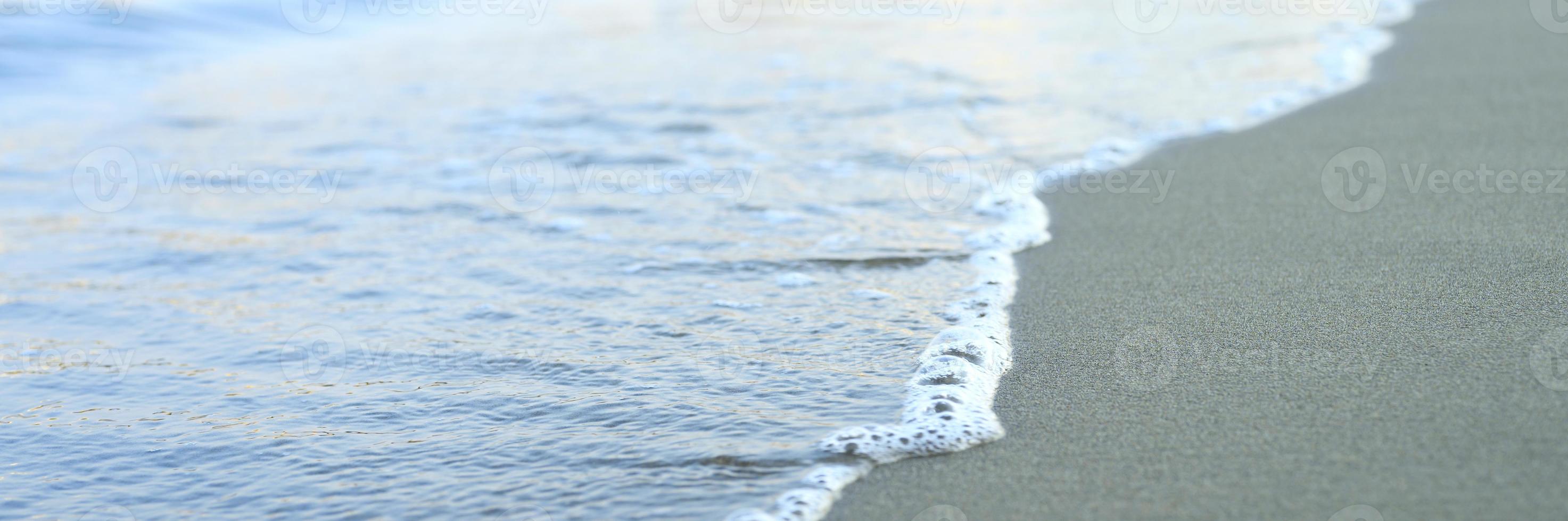 verschwommene Welle des Meeres am abendlichen Sandstrand foto