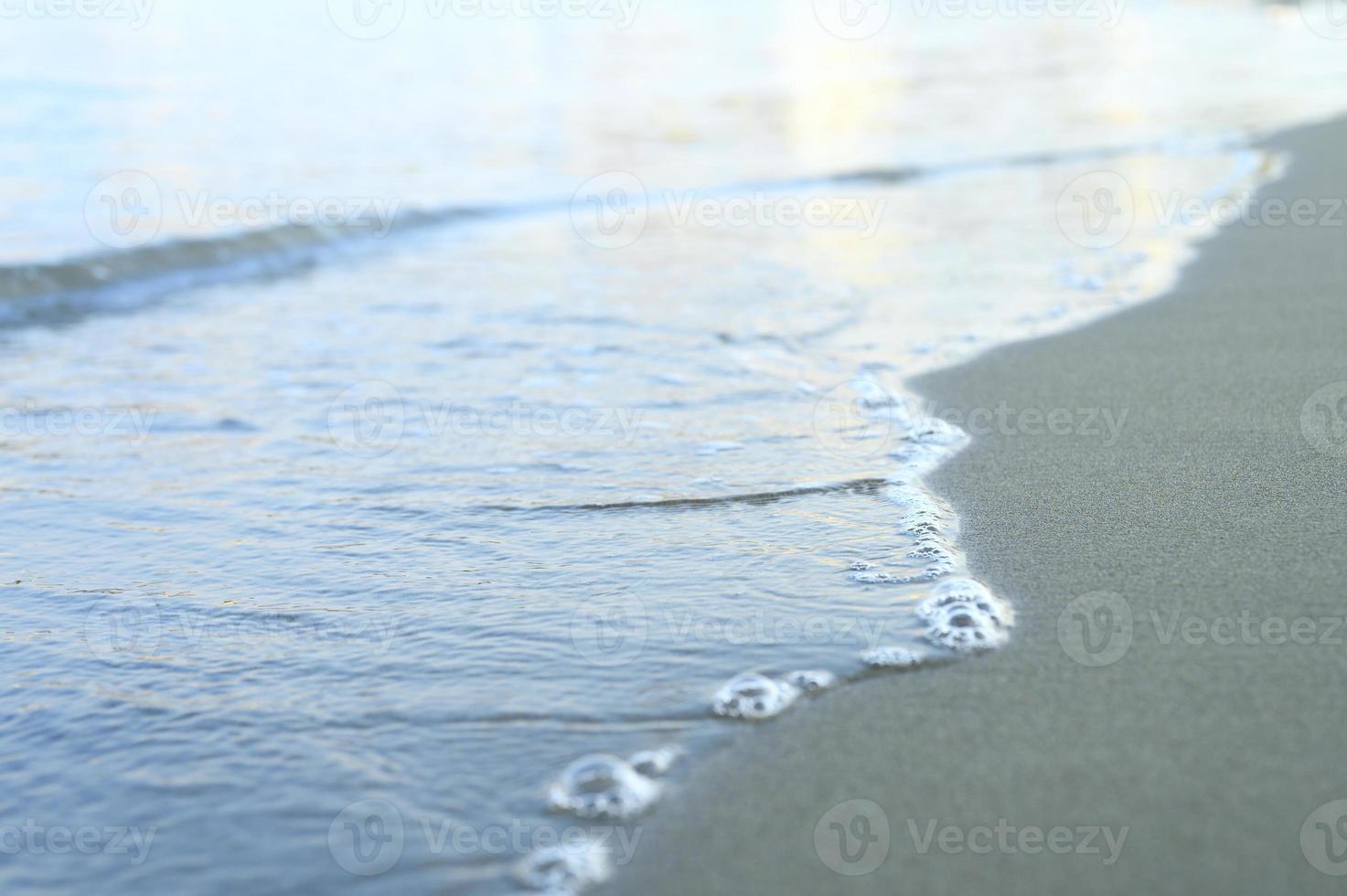 verschwommene Welle des Meeres am abendlichen Sandstrand foto