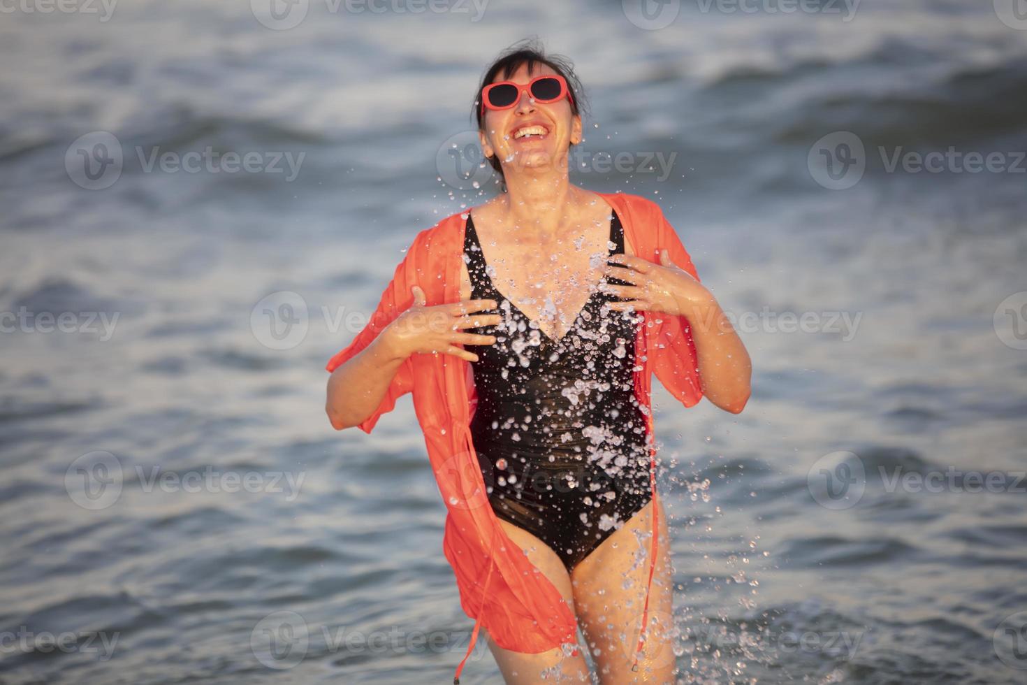 glücklich Frau beim das Meer mit spritzt foto