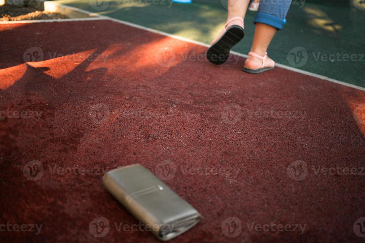 das Frau hat verloren ihr Leder Brieftasche mit Geld auf das Straße. Nahansicht von ein Brieftasche Lügen auf das Bürgersteig. foto