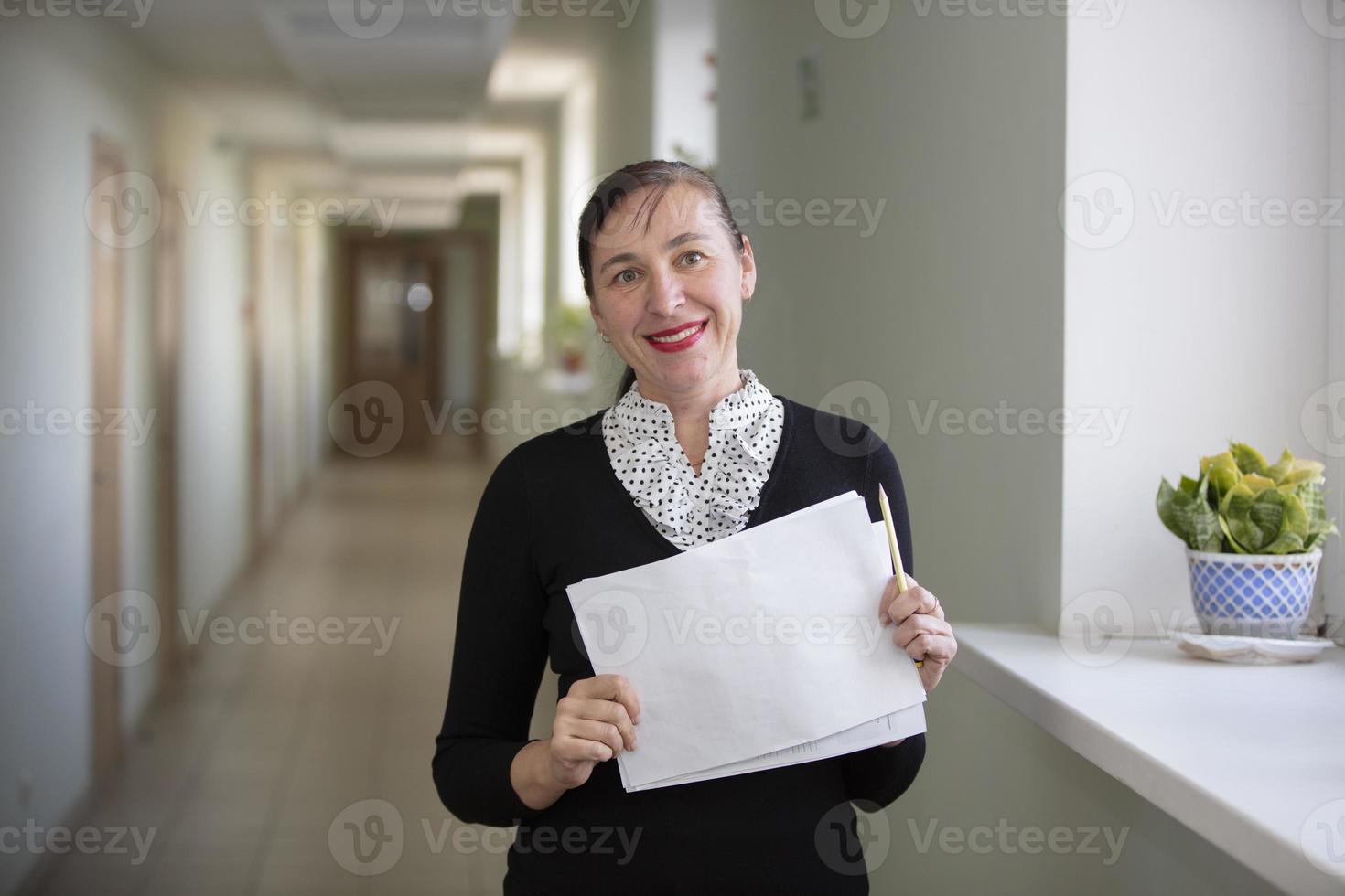 glücklich Frau beim arbeiten. weiblich Mitarbeiter im das Flur mit ein Stück von Papier. foto