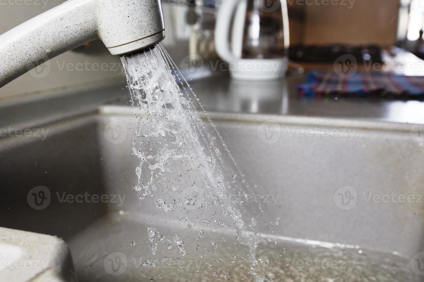 Wasser ist Gießen von ein Wasserhahn. Wasser Zapfhahn auf das Hintergrund von das Küche. Wasser sparen. foto