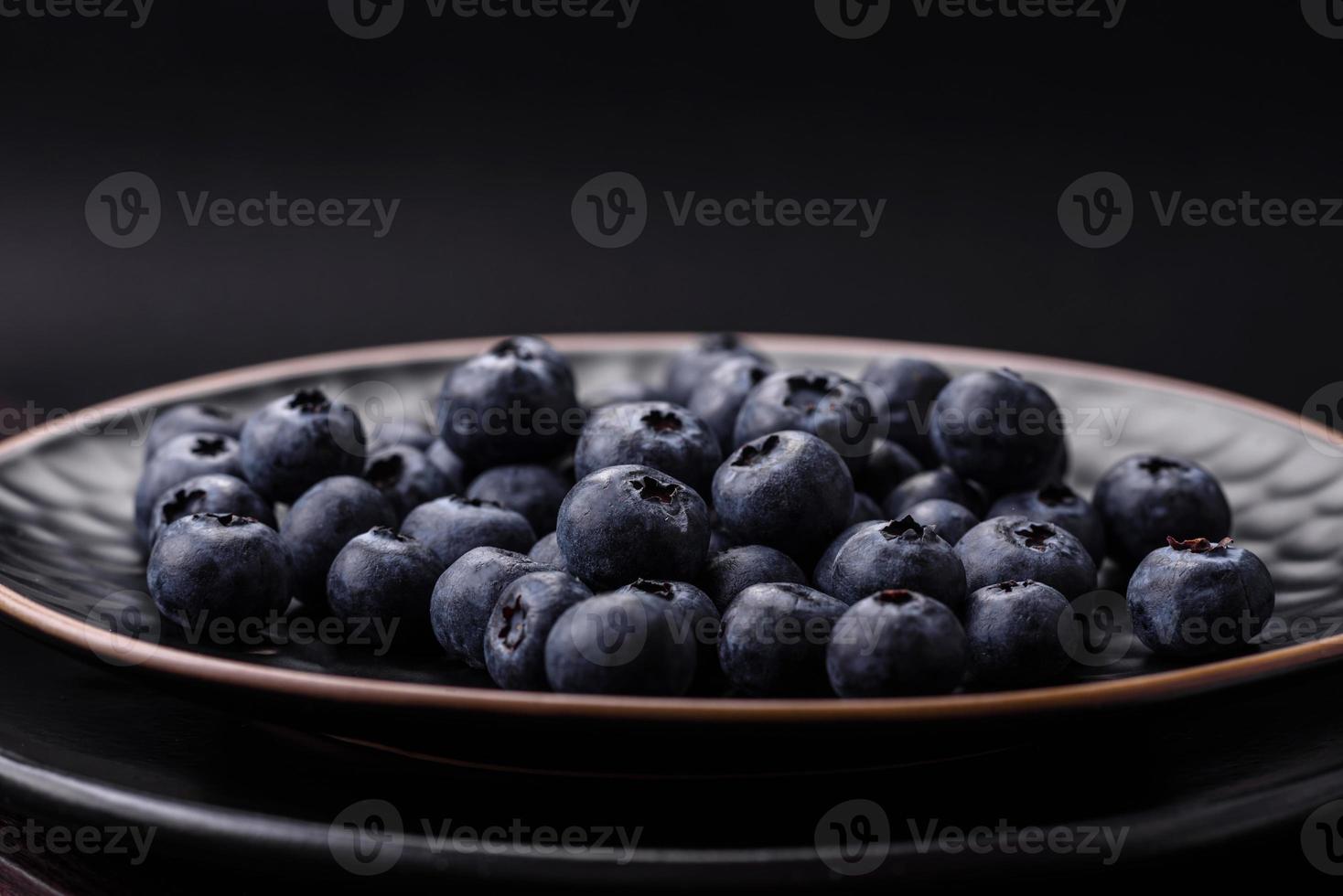 köstlich frisch Blaubeeren auf ein strukturell schwarz Beton Hintergrund foto