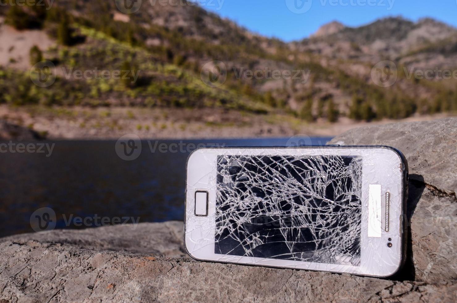 kaputtes Telefon auf einem Felsen foto