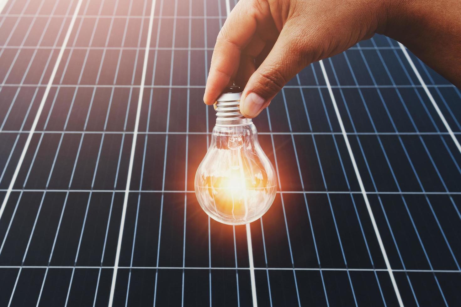 Hand halten die Glühbirne mit Solar- Panel Hintergrund. sauber Energie im Natur Konzept foto