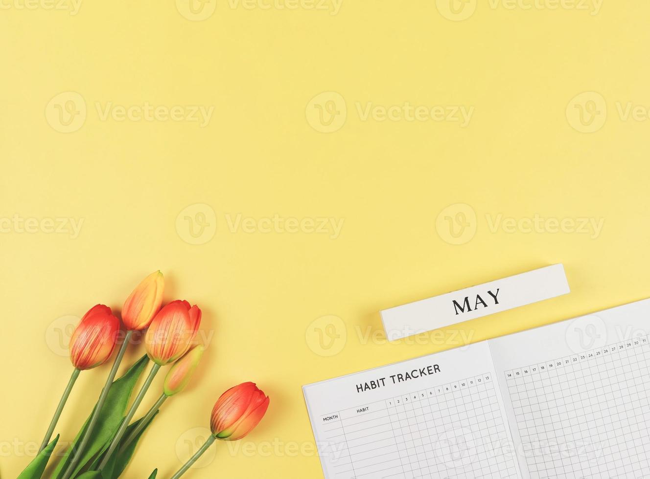eben Layout von Gewohnheit Tracker Buch, hölzern Kalender dürfen, und Tulpen auf Gelb Hintergrund mit Kopieren Raum. foto