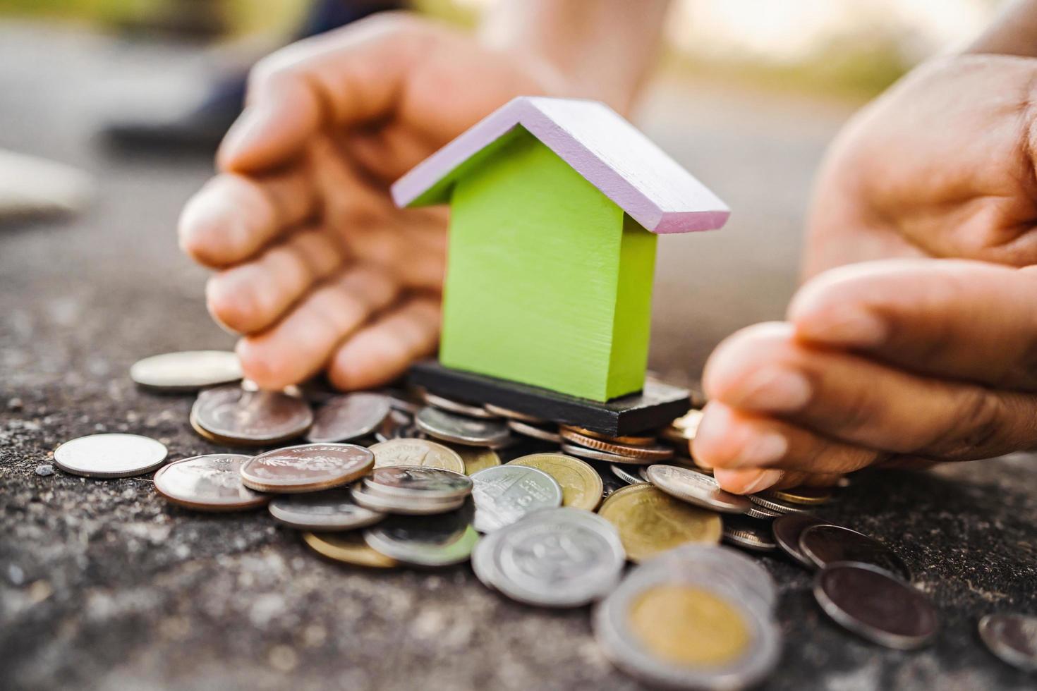 Hand schützen Geld und Mini Haus. cocept Speichern foto