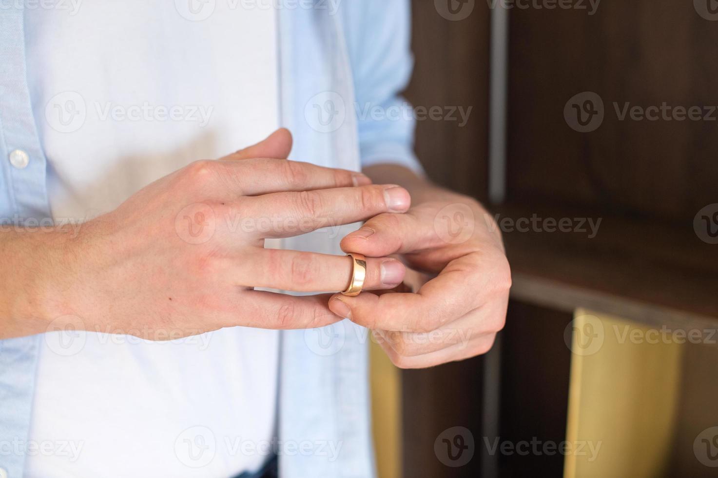 ein Geschäft Mann entfernt ein Gold Hochzeit Ring von seine richtig Hand foto