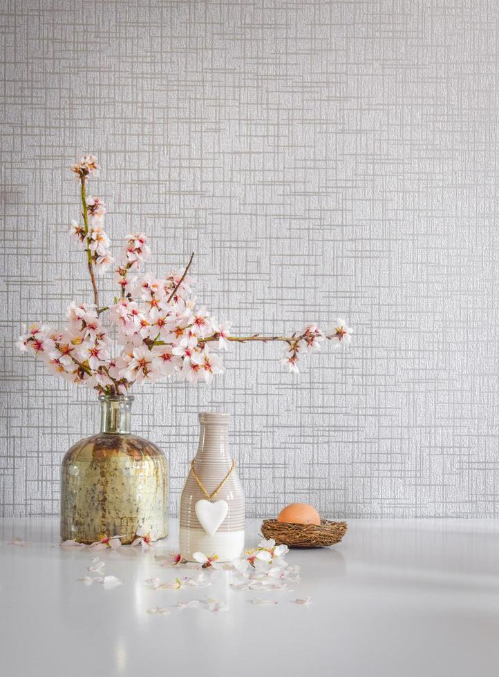 Weißer Küchentisch im Bouquet-Stil mit gelben und grünen Tassen, blühenden Gänseblümchenblumen und einem Osterei foto