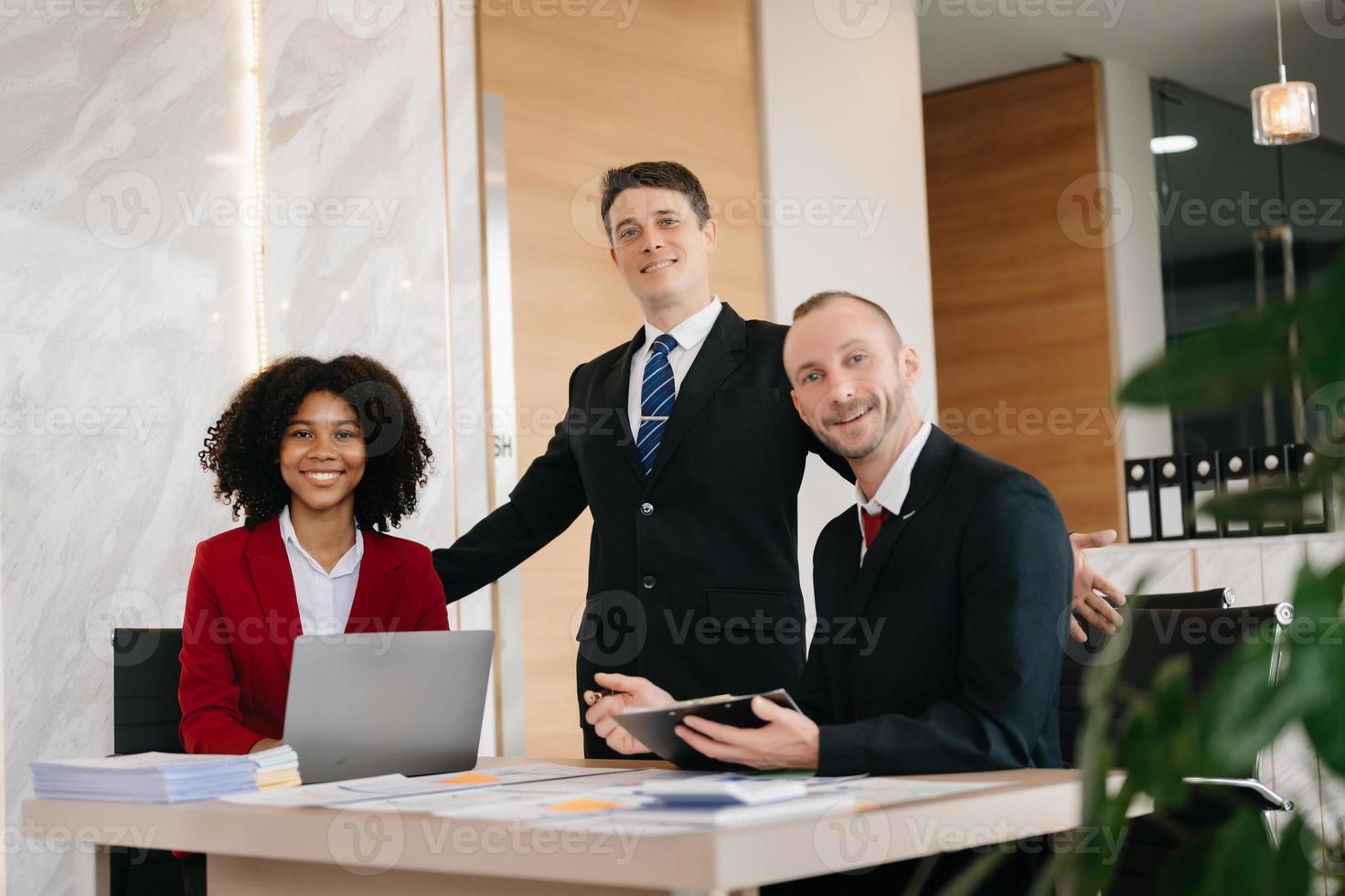 glückliche Geschäftsleute bei der Zusammenarbeit an einem neuen Projekt in einem Büro. gruppe verschiedener geschäftsleute, die einen laptop und ein tablet im büro verwenden. foto