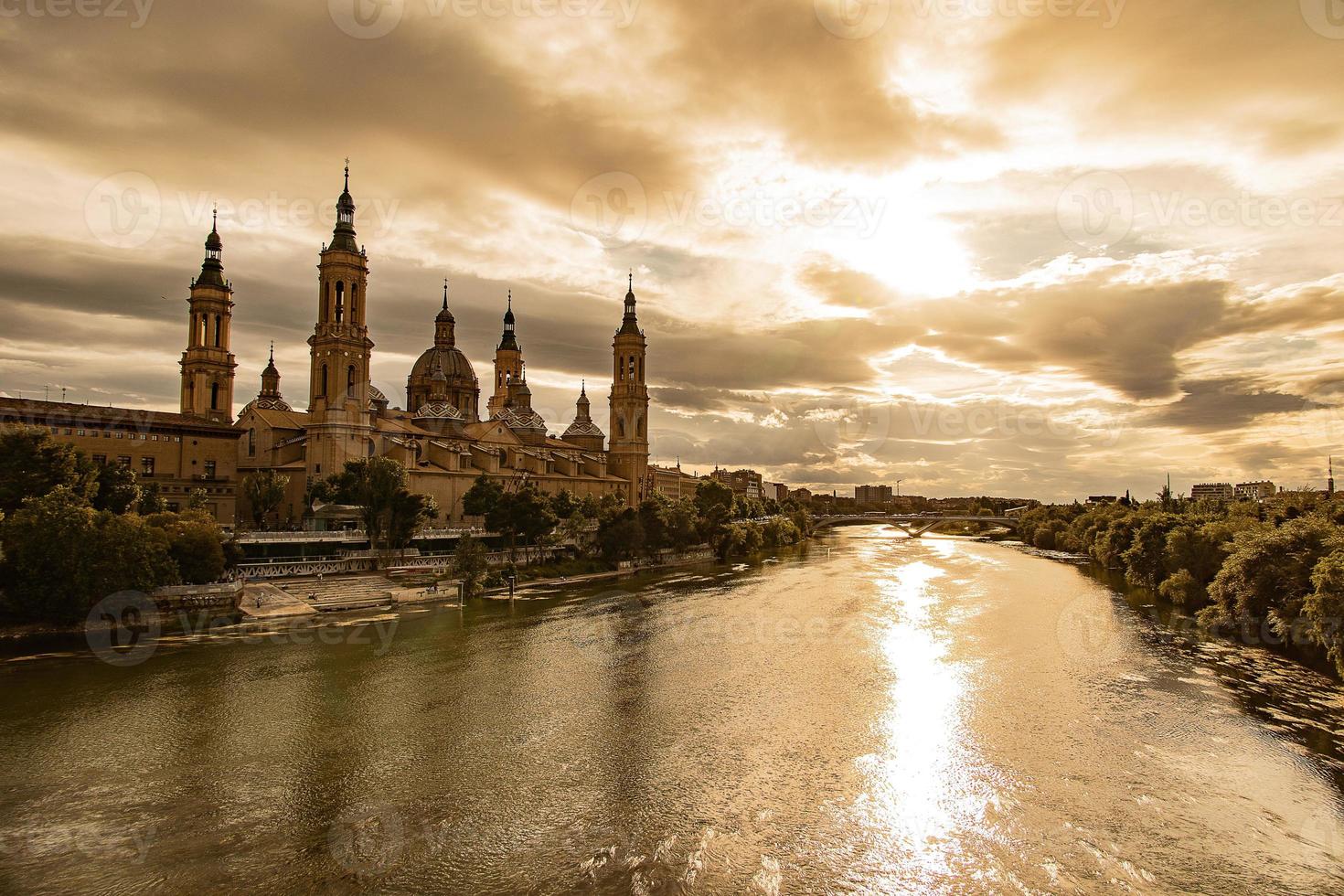 Landschaft von das Spanisch Stadt von Saragossa mit das Basilika und das ebro Fluss im das Hintergrund von das Sonne Rahmen im das Himmel foto