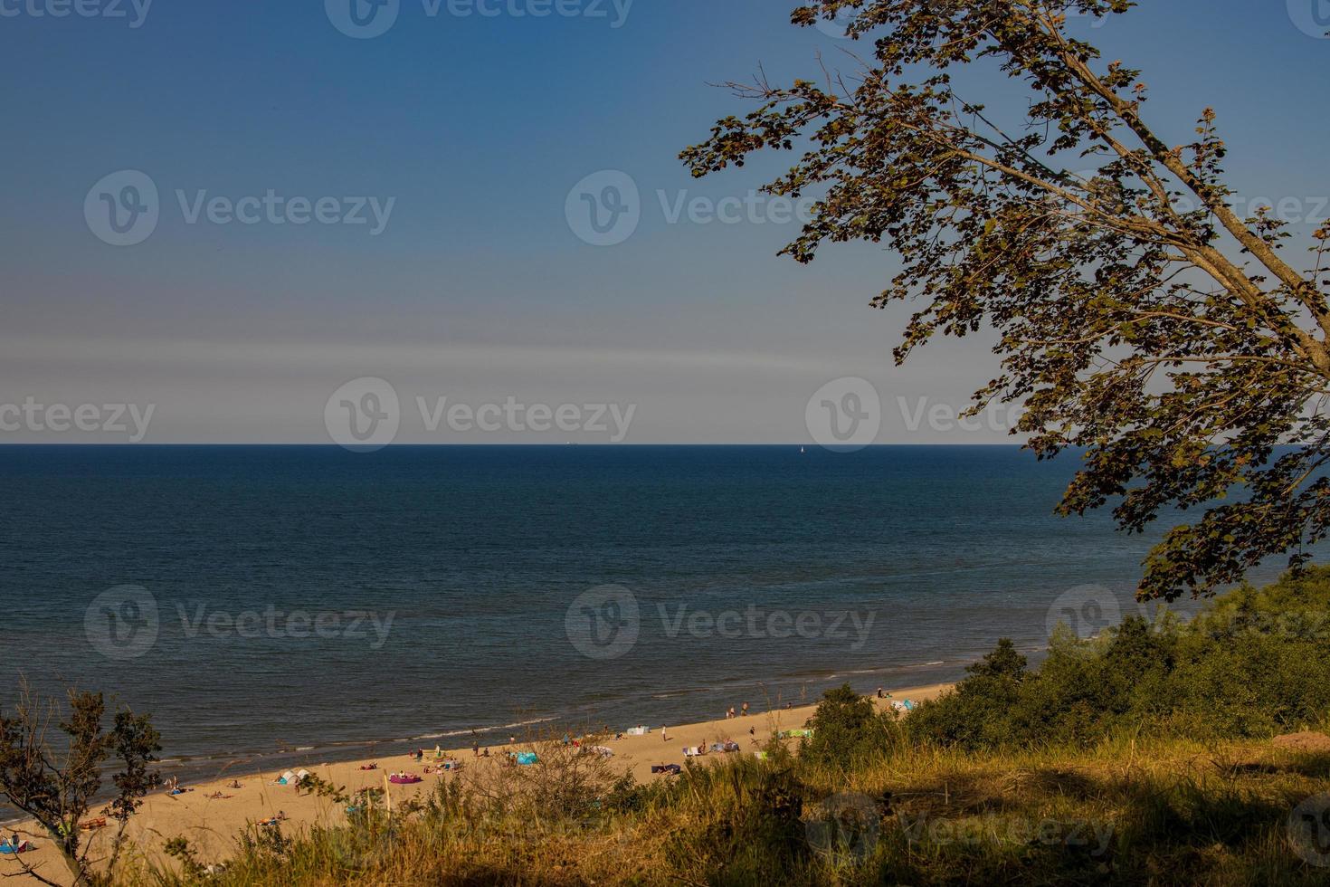 Aussicht von das Böschung zu das Strand auf das baltisch Meer auf ein Sommer- Tag mit Menschen foto