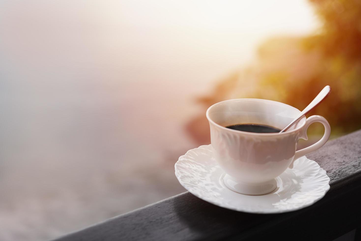 Morgenkaffee auf einem Balkon mit Sonnenaufgang und Sonnenstrahlen foto