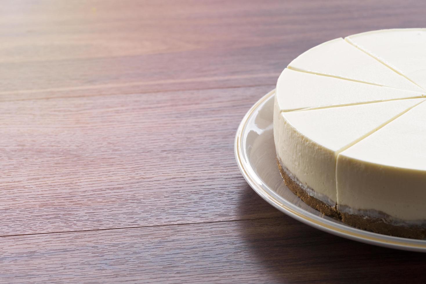 Käsekuchen auf einem weißen Teller auf einem Holztisch foto