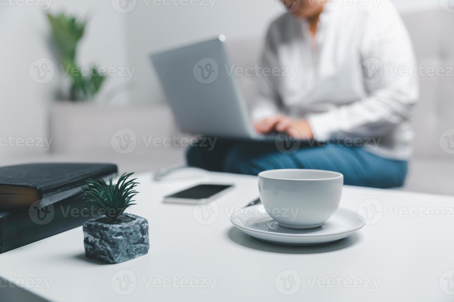 Sozial Medien Tag Konzept. weiblich Freiberufler beginnend Arbeiten Tag früh im Morgen Trinken Kaffee im Leben Zimmer zum Webseite mit mit modern Laptop Computer. Geschäftsfrau Arbeiten im Zuhause Büro. foto