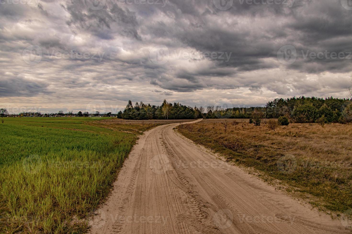 Frühling Landschaft mit ein Schmutz Straße, Felder, Bäume und Himmel mit Wolken im Polen foto
